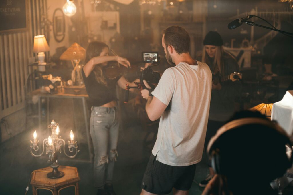 Director with camera and crew on a dimly lit movie set, capturing a scene.